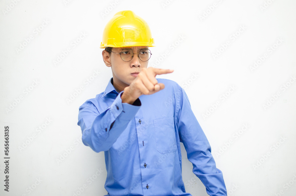 asian male construction worker or engineer in blue shirt and safety yellow helmet shows expresion of anger, furious and dissapointment isolated over white. stressed over work concept asian male construction worker or engineer in blue shirt and safety yellow helmet shows expresion of anger, furious and dissapointment isolated over white. stressed over work concept