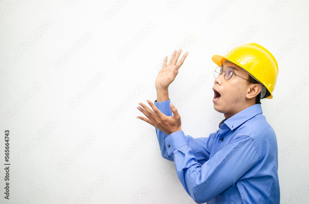 side view of A happy, shocked asian consrtuction worker in blue shirt and yellow safety helmet pointing finger and presenting something ads. side view of A happy, shocked asian consrtuction worker in blue shirt and yellow safety helmet pointing finger and presenting something ads.