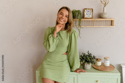 Canvas Print young stylish smiling woman in green summer dress in modern interior apartment h