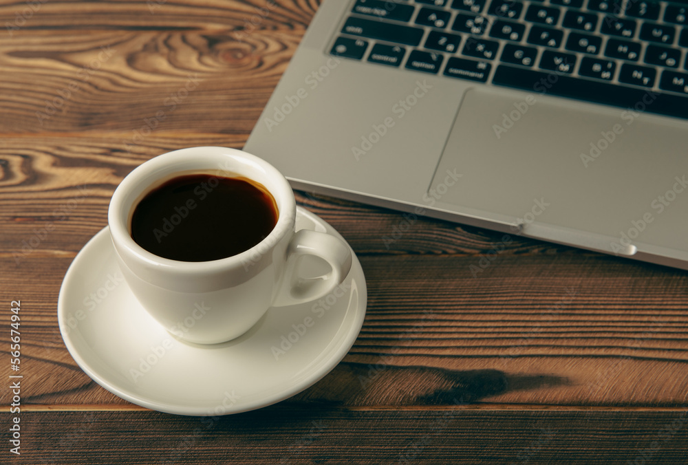 Work desk with a cup of hot fragrant espresso coffee and a laptop, on a textured wooden table. Office space. Flat lay, side view. copy spce.Place for text. Work desk with a cup of hot fragrant espresso coffee and a laptop, on a textured wooden table. Office space. Flat lay, side view. copy spce.Place for text.