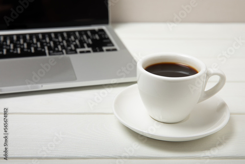 Work desk with a cup of hot fragrant espresso coffee and a laptop  on a textured wooden table. Office space. Flat lay  side view. copy spce.Place for text.