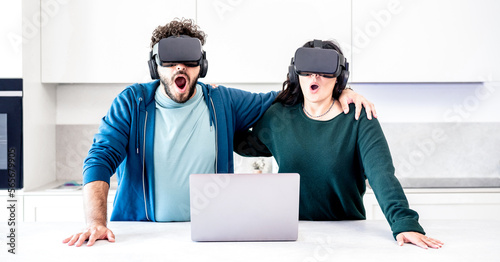 Millennial couplr playing with vr glasses at home kitchen - Virtual reality and tech concept with engaged people having fun throug headset goggle - Generation z digital trends - Bright azure filter photo