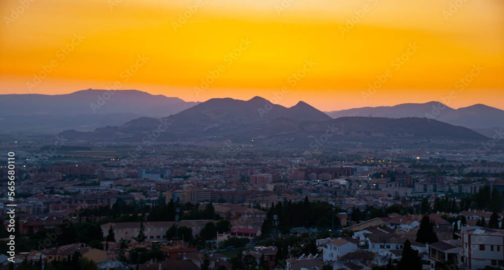 A beautiful firey orange sunset over the hills and city of Granada, Spain
