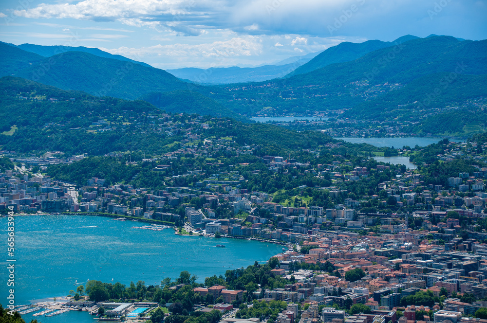 Lugano and its lakes, a town in Switzerland is at the base of a mountain in a valley on a sunny summer day