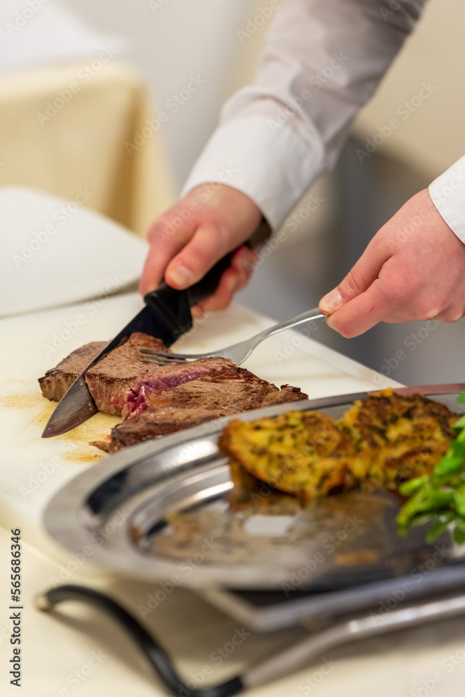 Découpage d'une pièce de viande de boeuf au couteau devant le client. Détail