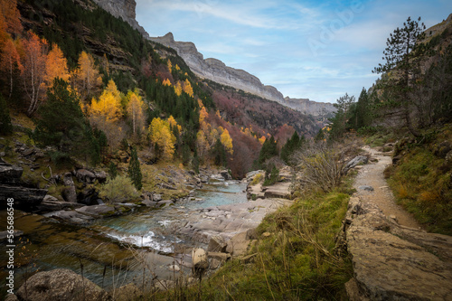Autumn landscape in the Ordesa y Monte Perdido national park in the Pyrenees, in Huesca, Spain, where you can see a path for hikers and a blue river
