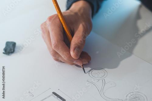 Close-up of a bright, businesslike, aspiring and young architect at his desk in his office. Drawing a new product on white paper. Work of a product designer. Searching for an idea, finding inspiration