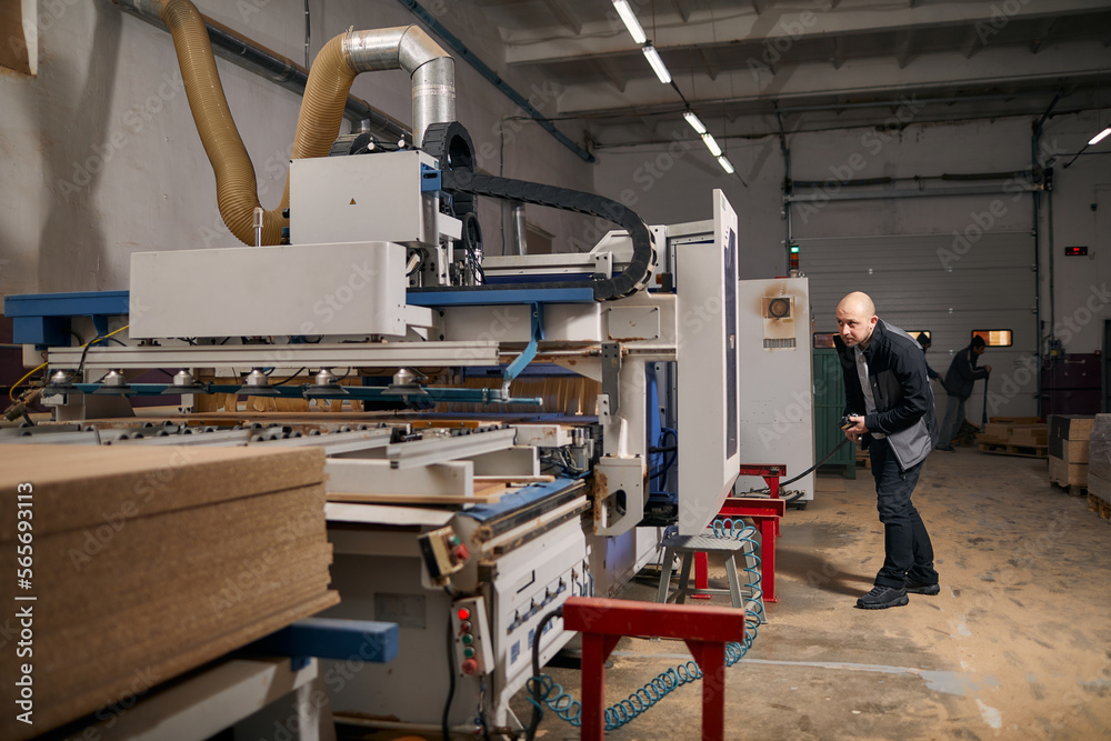 A young man stands in a furniture shop near the machine A young man stands in a furniture shop near the machine
