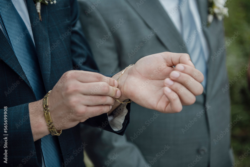 A closeup shot of a groom fixing his bracelet during his wedding
