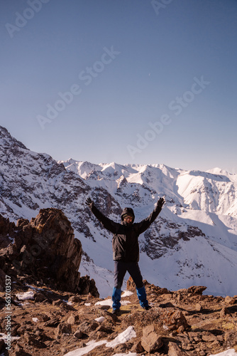 the guy poses for the camera against the backdrop of a mountain landscape