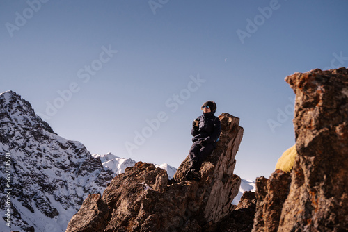 a man sits on a rock against the backdrop of snow-capped mountains with paper cups of coffee
