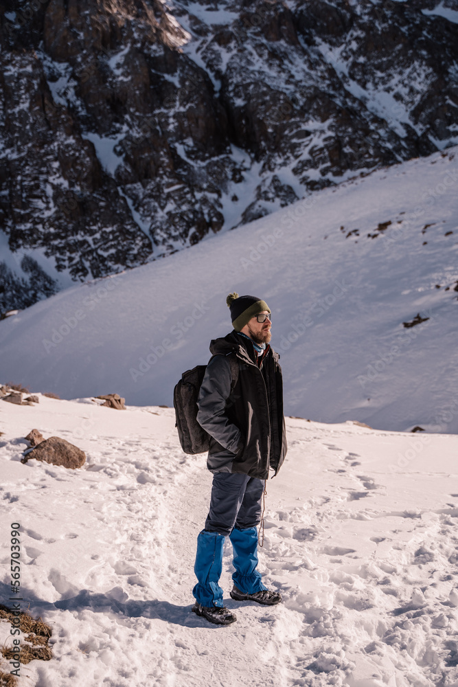a male tourist stands on a snowy path in the mountains
