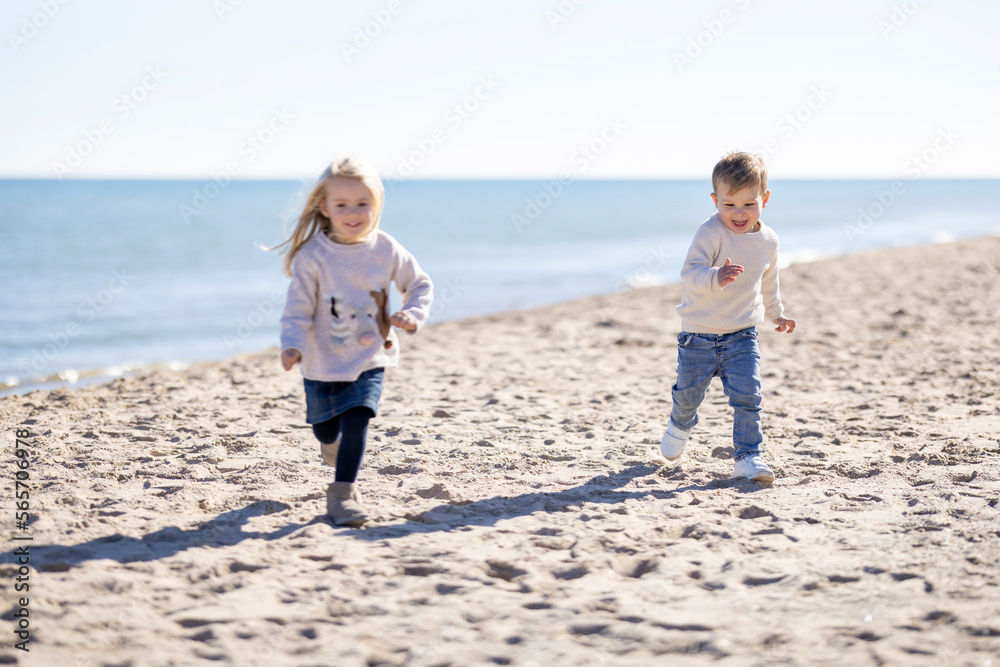 Little girl and little boy having fun and running on the beach Little girl and little boy having fun and running on the beach