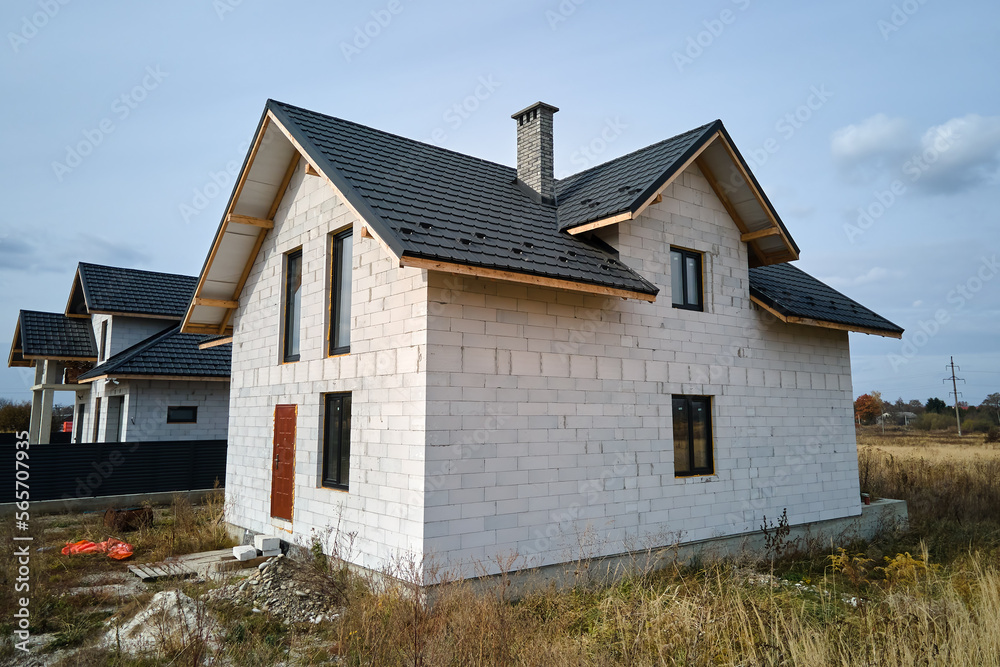 Aerial view of unfinished house with aerated lightweight concrete walls and wooden roof frame covered with metallic tiles under construction