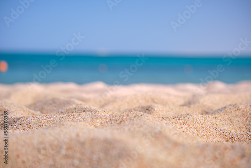 Close up of clean yellow sand surface covering seaside beach with blue sea water on background. Travel and vacations concept © bilanol