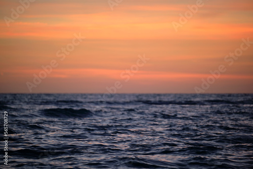 Dramatic red ocean waves at sunset with soft evening sea dark water