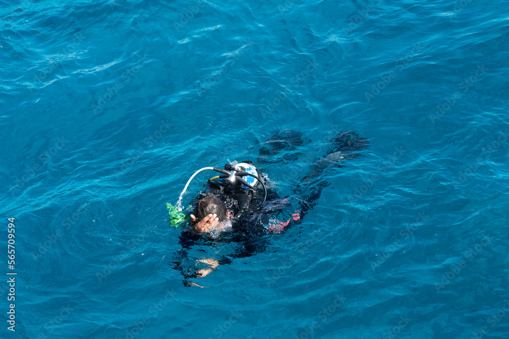 Diver with scuba swimming in Red sea blue water, Egypt