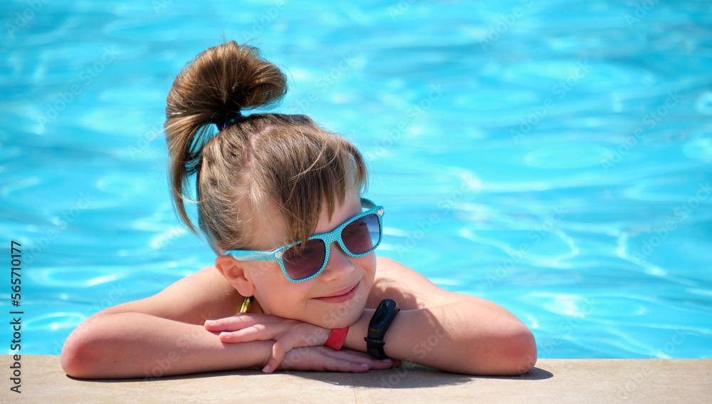 Young joyful child girl resting on swimming pool side with clear blue water on sunny summer day. Tropical vacations concept