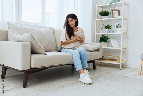 Woman sitting on sofa at home arm and shoulder pain, muscle sprain and joint pain, calcium problems in bones