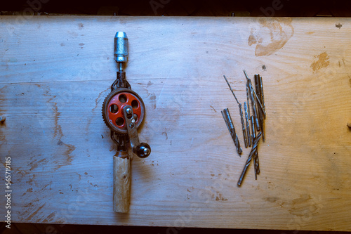 Old hand drill and drills. Old hand tools and spare parts. Old working wooden table. photo