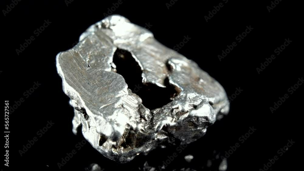 Rotating Of An Iron Meteorite. black background on a mirror base. Close-up. Macro Rotating Of An Iron Meteorite. black background on a mirror base. Close-up. Macro