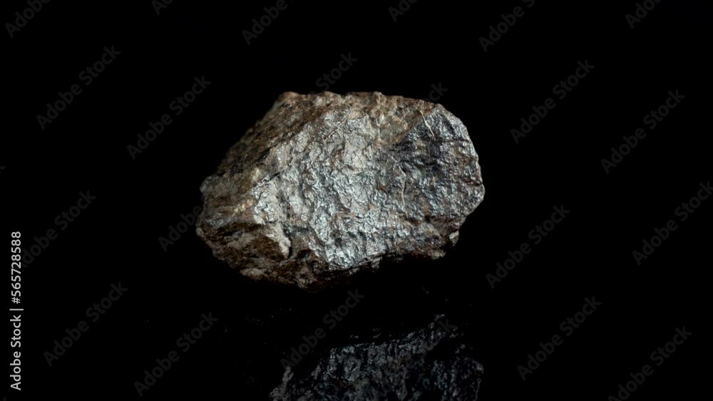Rotating Of An Iron Meteorite. black background on a mirror base. general plan.