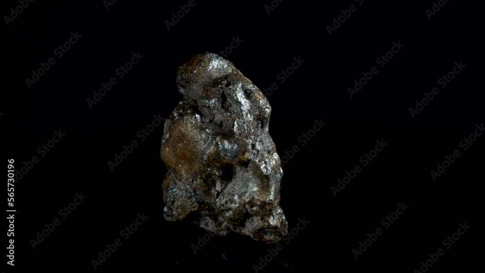 Rotating Of An Iron Meteorite. black background on a mirror base. general plan.