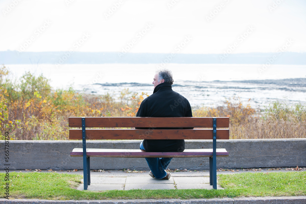 Rear view of mature man overlooking river in Autumn alone. Rear view of mature man overlooking river in Autumn alone.