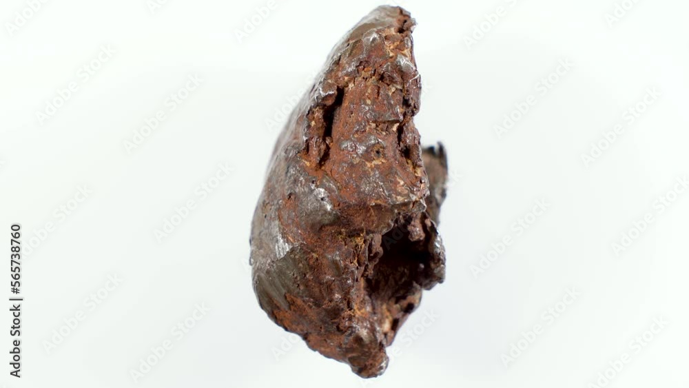Rotating Of An Iron Meteorite. White background on a white base. general plan. Rust on the surface Rotating Of An Iron Meteorite. White background on a white base. general plan. Rust on the surface