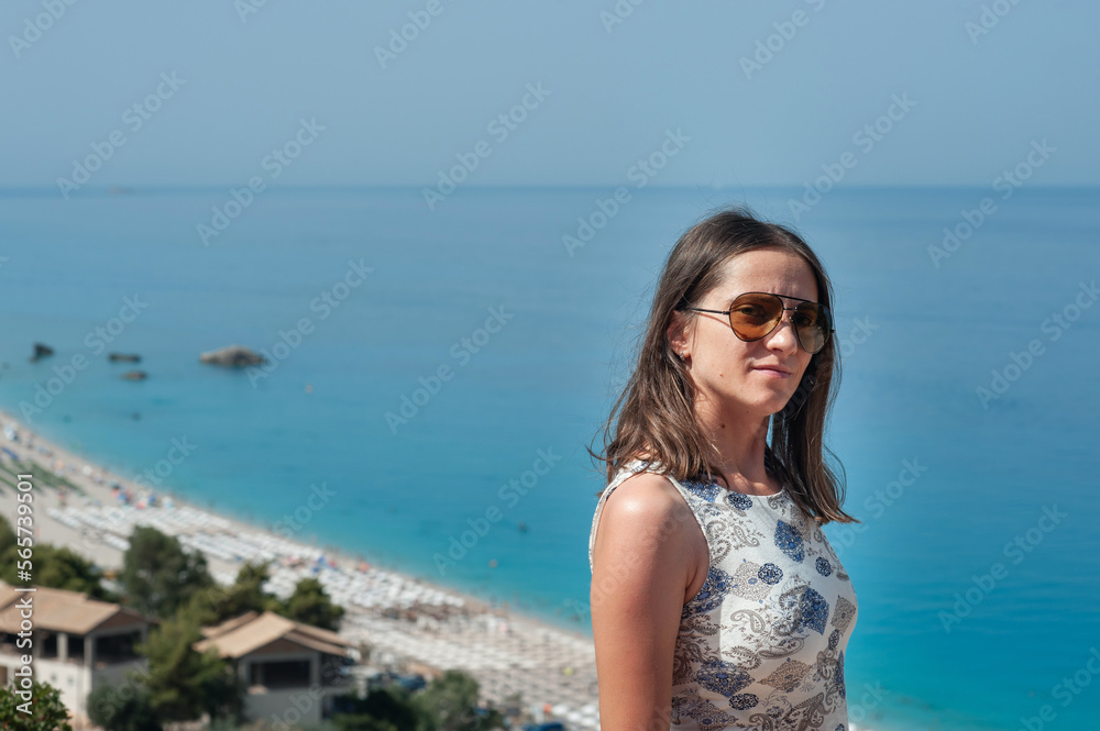 A young woman is standing on the cliff that overlooks Kathisma beach
