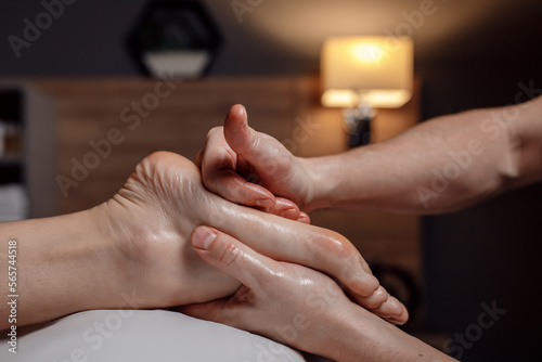 Relaxing foot massage, hands of a female massage therapist massaging female client s foot