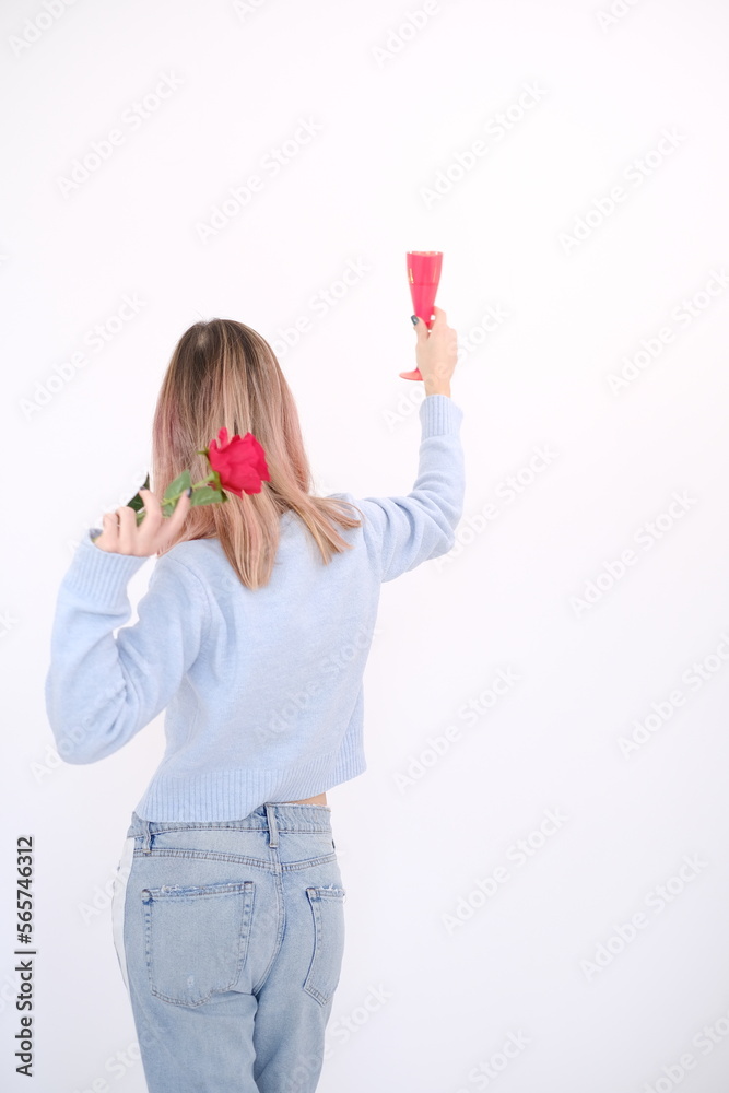 Young and attractive happy woman from her back, holding a rose and a glass of beverage on her hands. Single life. Happy girl. Freedom Young and attractive happy woman from her back, holding a rose and a glass of beverage on her hands. Single life. Happy girl. Freedom