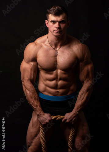 Muscled Male Model Flexes with Large Rope in Studio Setting