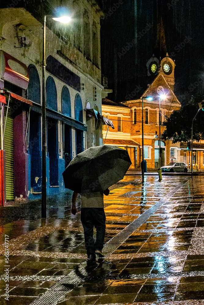 Homem caminha solitário com guarda-chuva em noite de intensa chuva na região da Estação Cultura. Homem caminha solitário com guarda-chuva em noite de intensa chuva na região da Estação Cultura.
