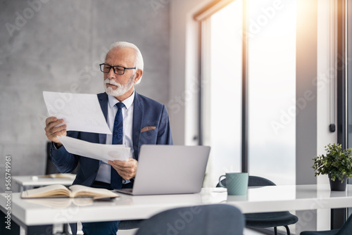 Senior male entrepreneur in suit working in office with laptop