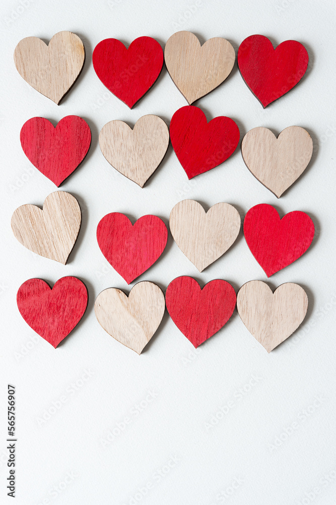 array of plain and painted red wooden hearts on blank paper