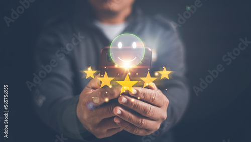 Customer satisfaction experience survey concept, Businessman using smartphone for select smiley face icon and five stars for client evaluation, rating very impressed, Most satisfaction rating.