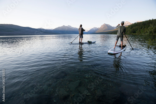 A man and woman stand up paddle boards (SUP) on Lake McDonald in Glacier National Park. photo