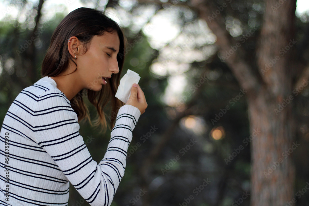 Health and medicine - Young woman sneezing in the woods. Health and medicine - Young woman sneezing in the woods.
