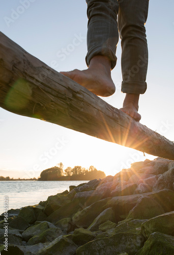 Feet balancing on log above river at sunrise photo