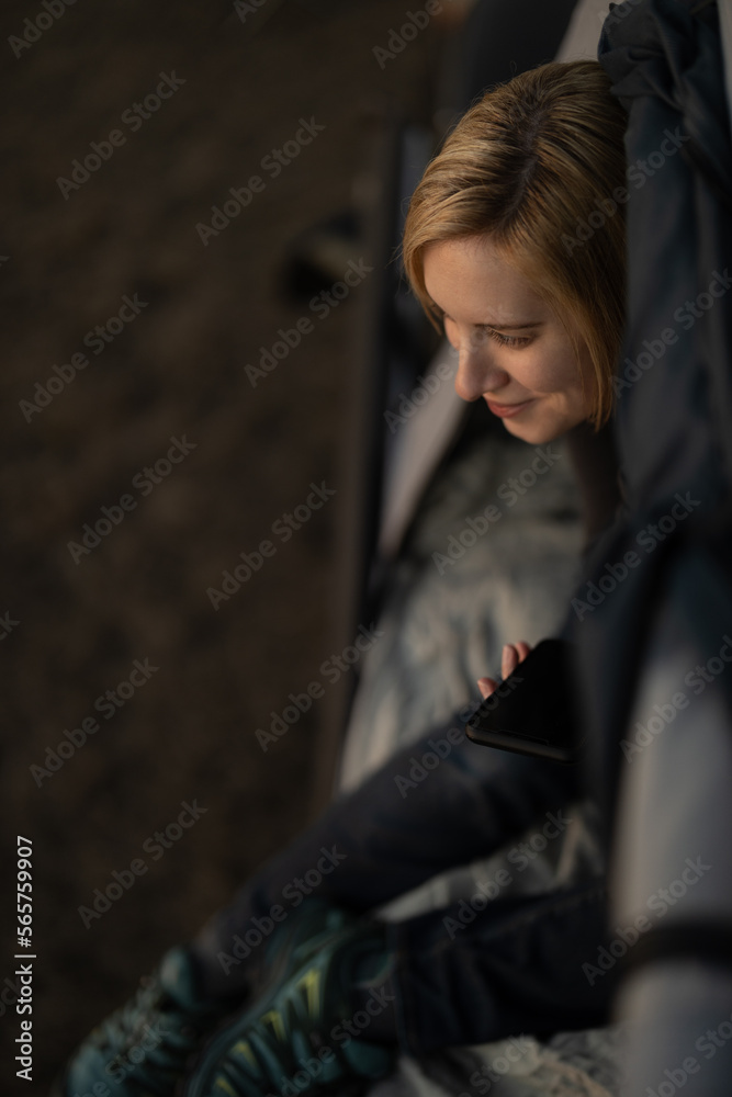 Woman talking on the phone in a tent while camping at sunset Woman talking on the phone in a tent while camping at sunset