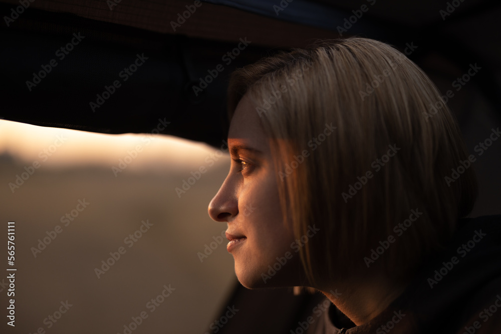 Woman sitting inside a tent while camping at sunset. Woman sitting inside a tent while camping at sunset.