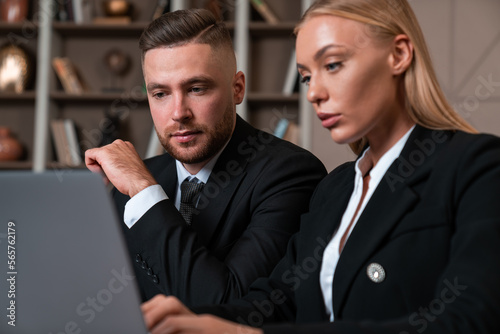 Businesswoman and businessman wearing formal wear sitting workin