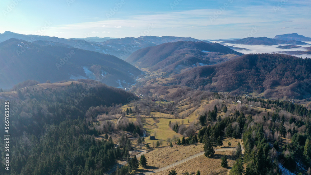 Aerial view of a small village in Carpathian Mountains of Romania. Thick mist covering a nearby valley