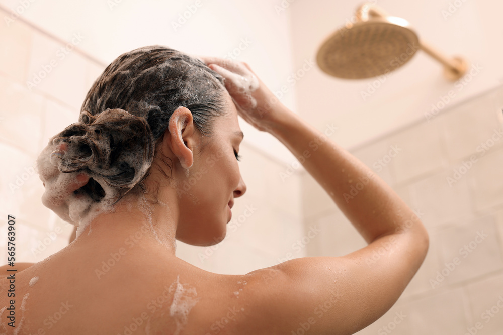 Naklejka premium Woman washing hair while taking shower at home, back view