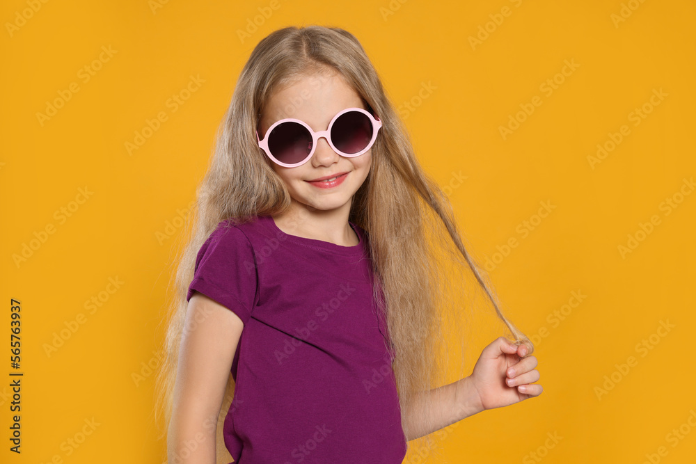 Fototapeta premium Girl in stylish sunglasses on orange background