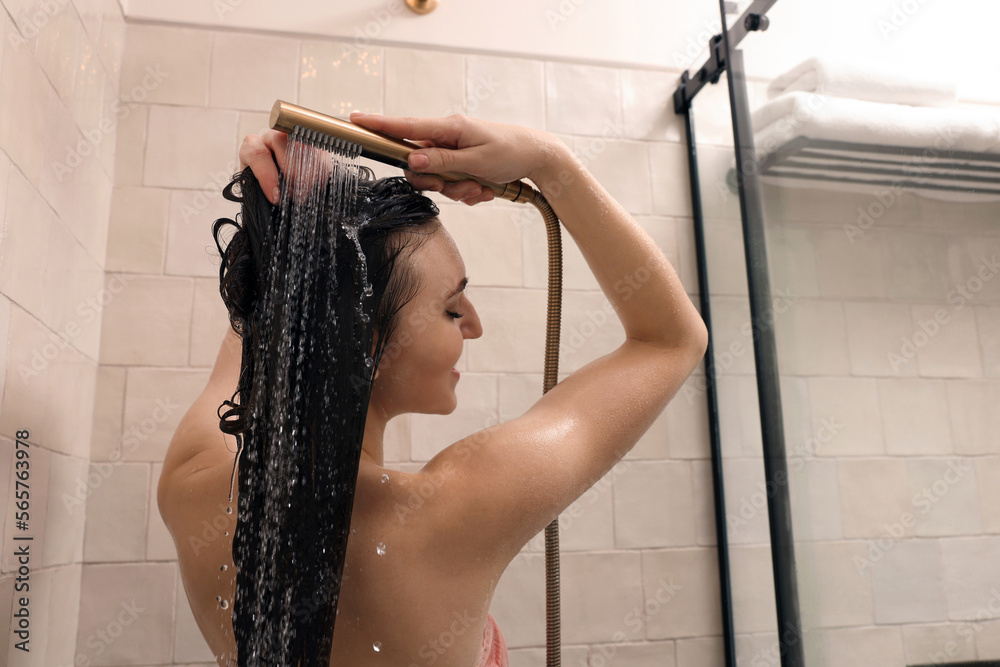 Young woman washing hair while taking shower at home Young woman washing hair while taking shower at home