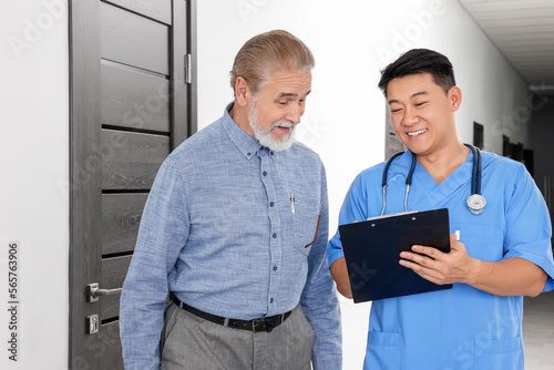 Doctor with clipboard consulting senior patient in clinic