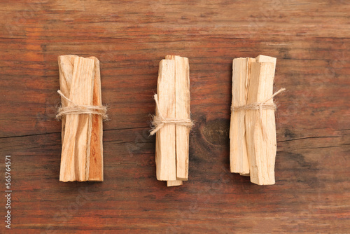 Bunches of tied Palo Santo sticks on wooden table, flat lay