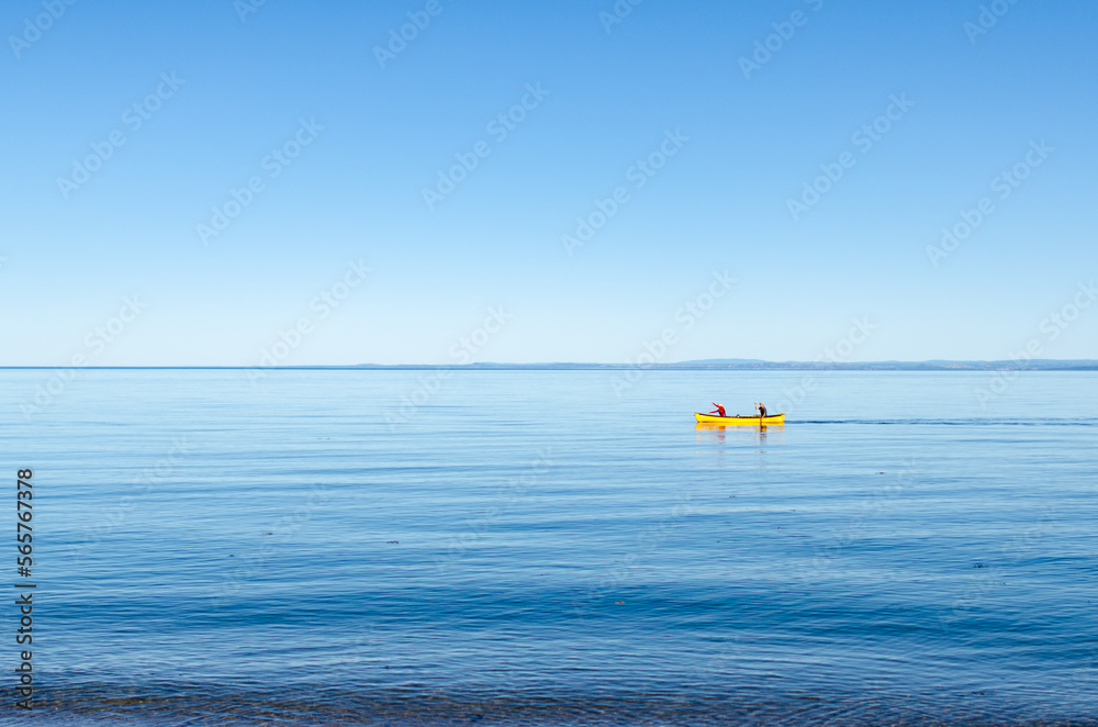 Couple paddling in a yellow canoe on the St-Lawrence river and on calm water